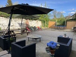Un patio con mobiliario exterior, una mesa de ping pong y un muro de piedra.