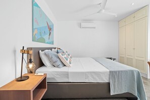 A modern bedroom with a bed, bedside table, lamp, and a large wardrobe.