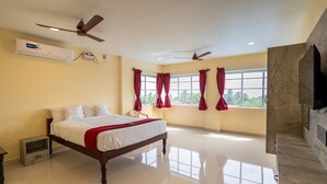 A spacious bedroom with a large bed, two ceiling fans, a window with red curtains, and a marble fireplace. - Sunlux Grand Residency (Vanur)