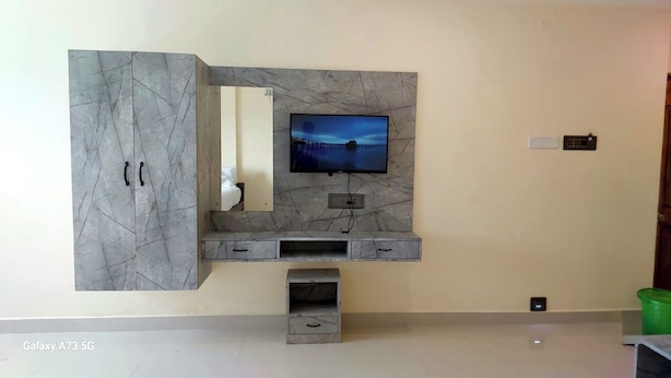 A modern living room with a marble-patterned entertainment unit, a flat-screen TV, and a built-in bench. - Sunlux Grand Residency (Vanur)