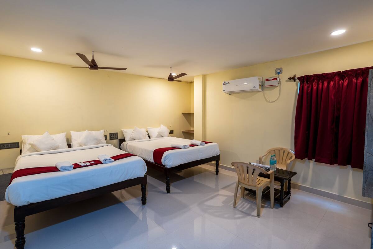 Habitación de hotel con dos camas, un escritorio, una silla, un aire acondicionado y un ventilador de techo.
