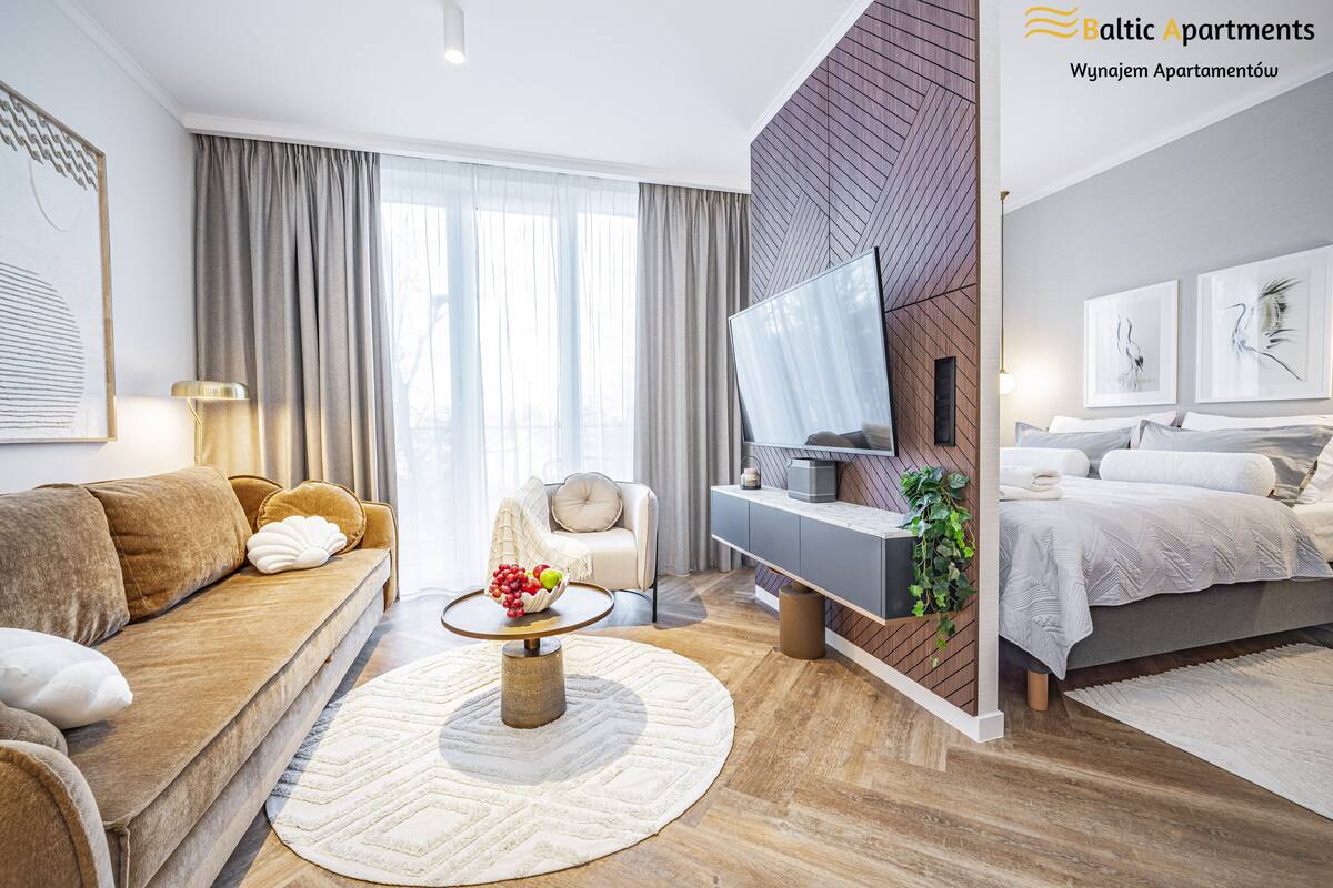 Een moderne woonkamer met een bank, een salontafel met fruit, een televisie en een bed met hoofdeinde.