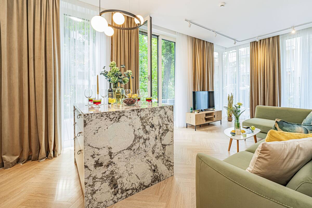 Een moderne woonkamer met een marmeren eiland, een groene bank en een televisie.