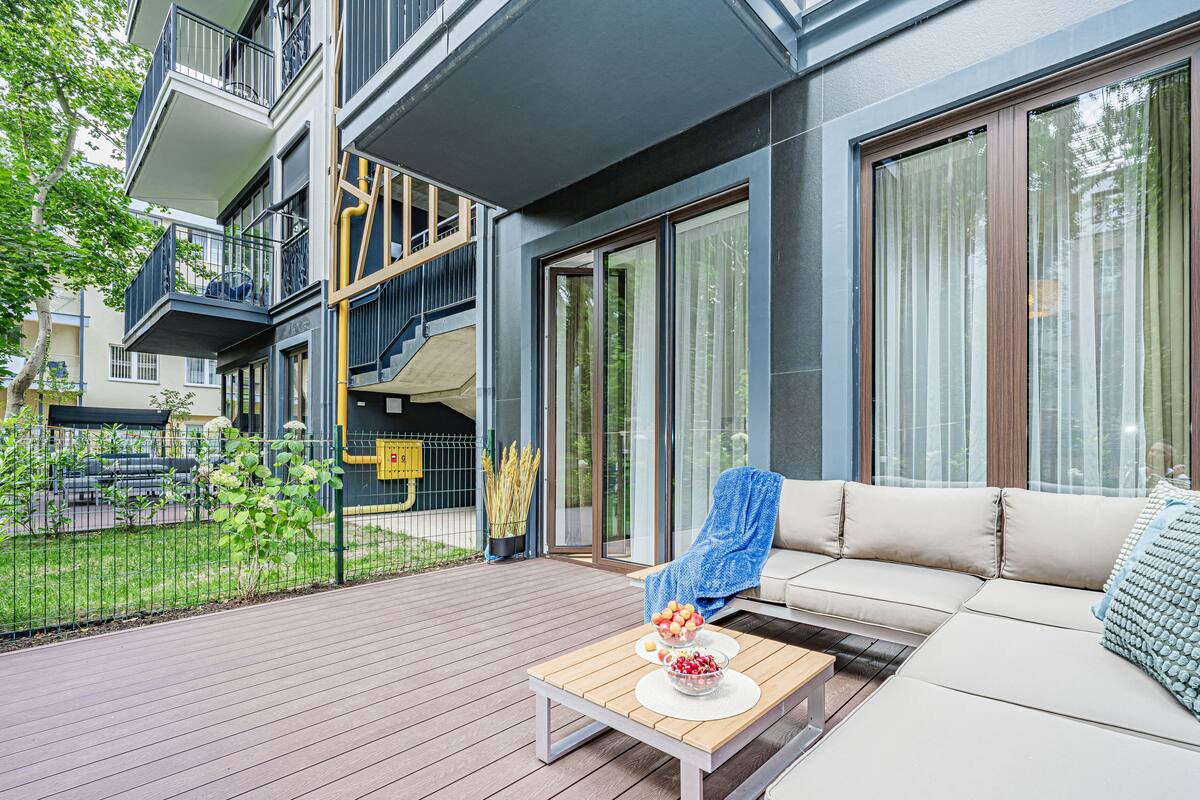 Een modern appartement met balkon, een bank en een tafel met fruitkommen.