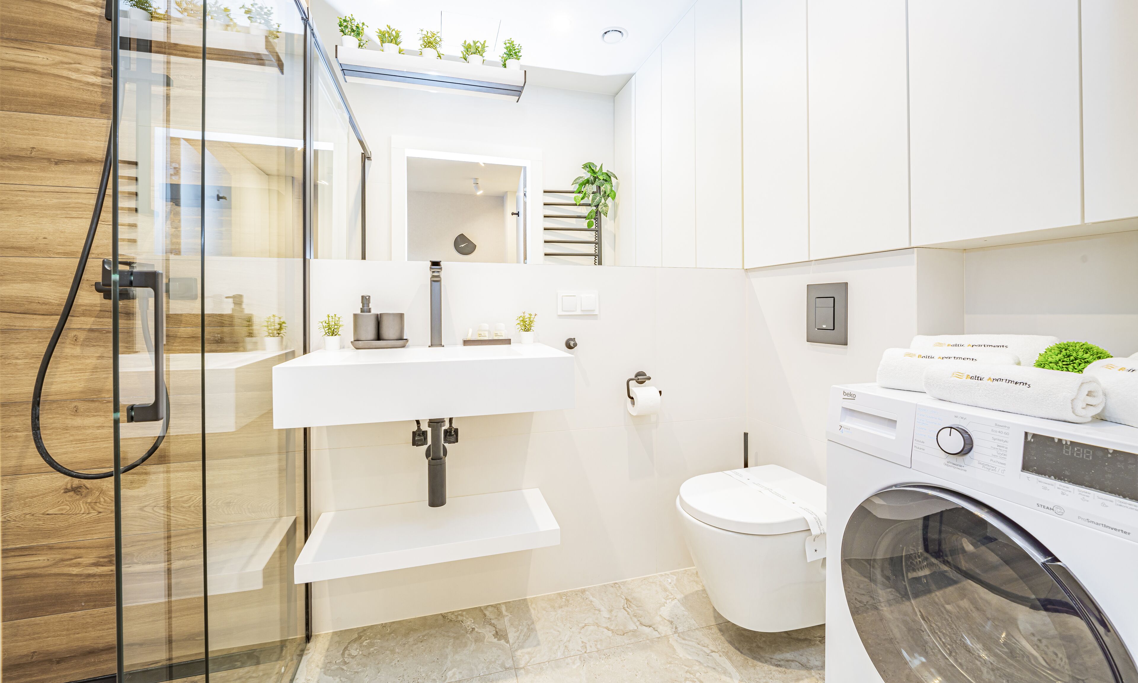 A modern bathroom with a glass shower enclosure, a white sink, a toilet, and a washing machine.