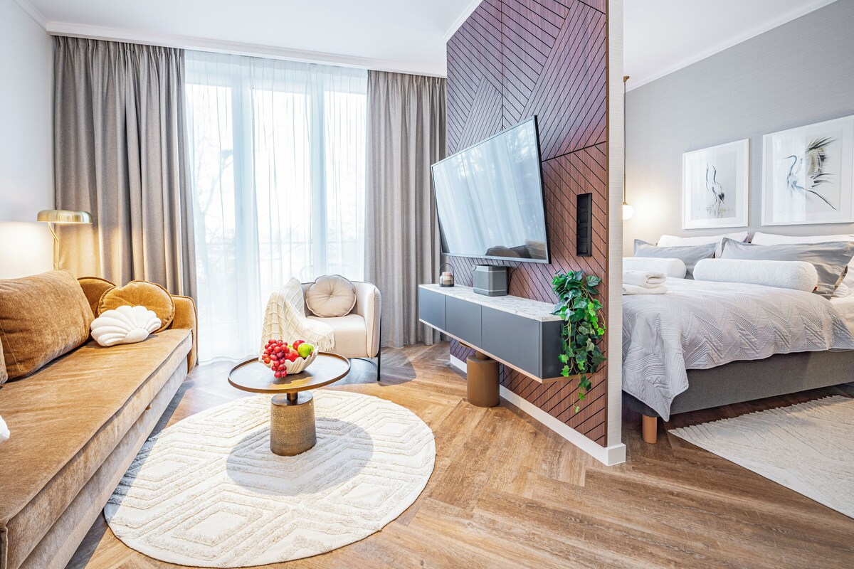 Een moderne woonkamer met een bank, een salontafel met fruit, een televisie en een bed met hoofdeinde.