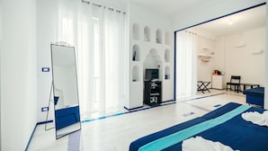 A hotel room with a large bed, a TV, a desk, and a chair. - Boutique Suite in Piazzetta (Capri)