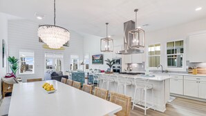 Una cocina amplia con armarios blancos, una isla central e iluminación colgante moderna.