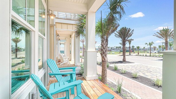 Un área de estar al aire libre techada con sillas Adirondack turquesa y una terraza de madera.