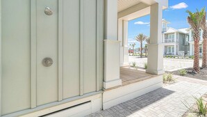 Un edificio moderno con un área exterior cubierta, una puerta visible y un camino pavimentado.