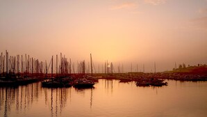 A marina with numerous boats docked, calm water reflecting the boats, and a sunset in the background. - Lovely home in Marina di Ragusa (Marina di Ragusa)