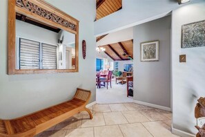 A hallway with a wooden bench, a mirror, and a door leading to a dining area.