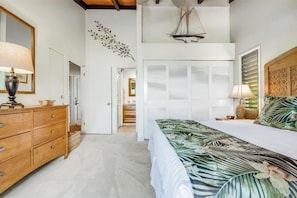 A bedroom with a bed, a wooden dresser, and a mirror.