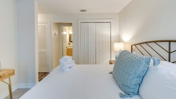 A neatly arranged bedroom with a bed, a bedside table, a lamp, and a closet. - Quaint Sarasota Condo: 4 Mi to Siesta Key Beach! (Sarasota)