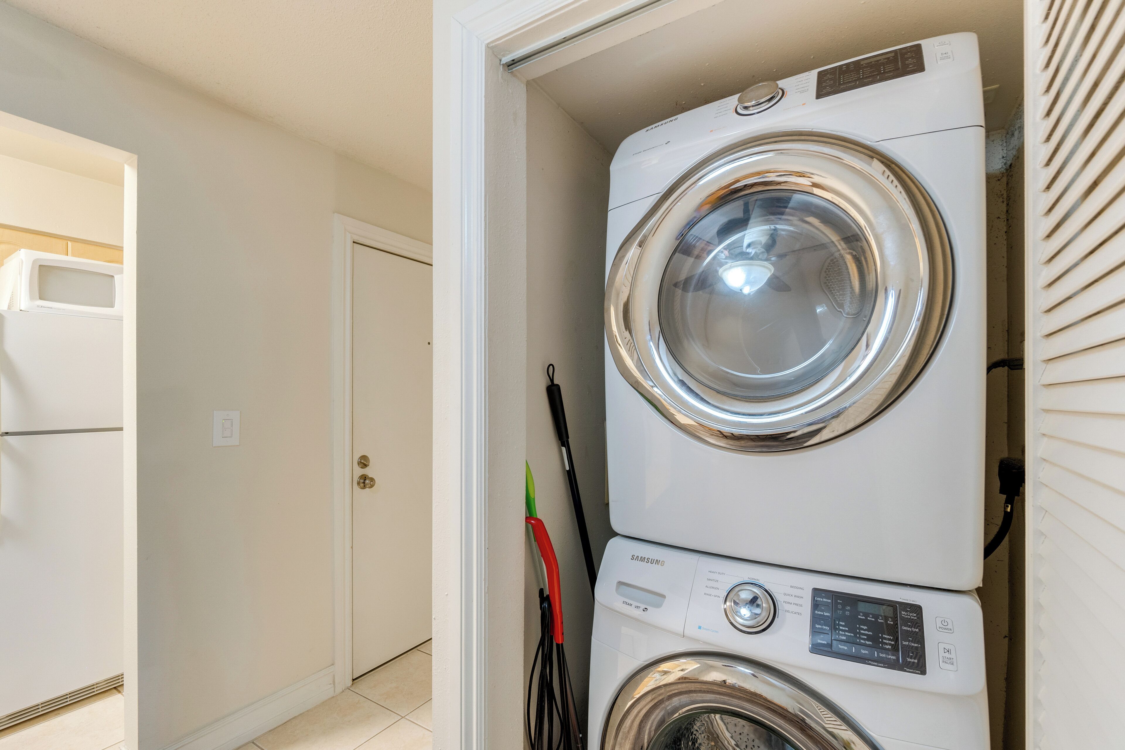 A laundry area with stacked washing machines and a door leading to another room.