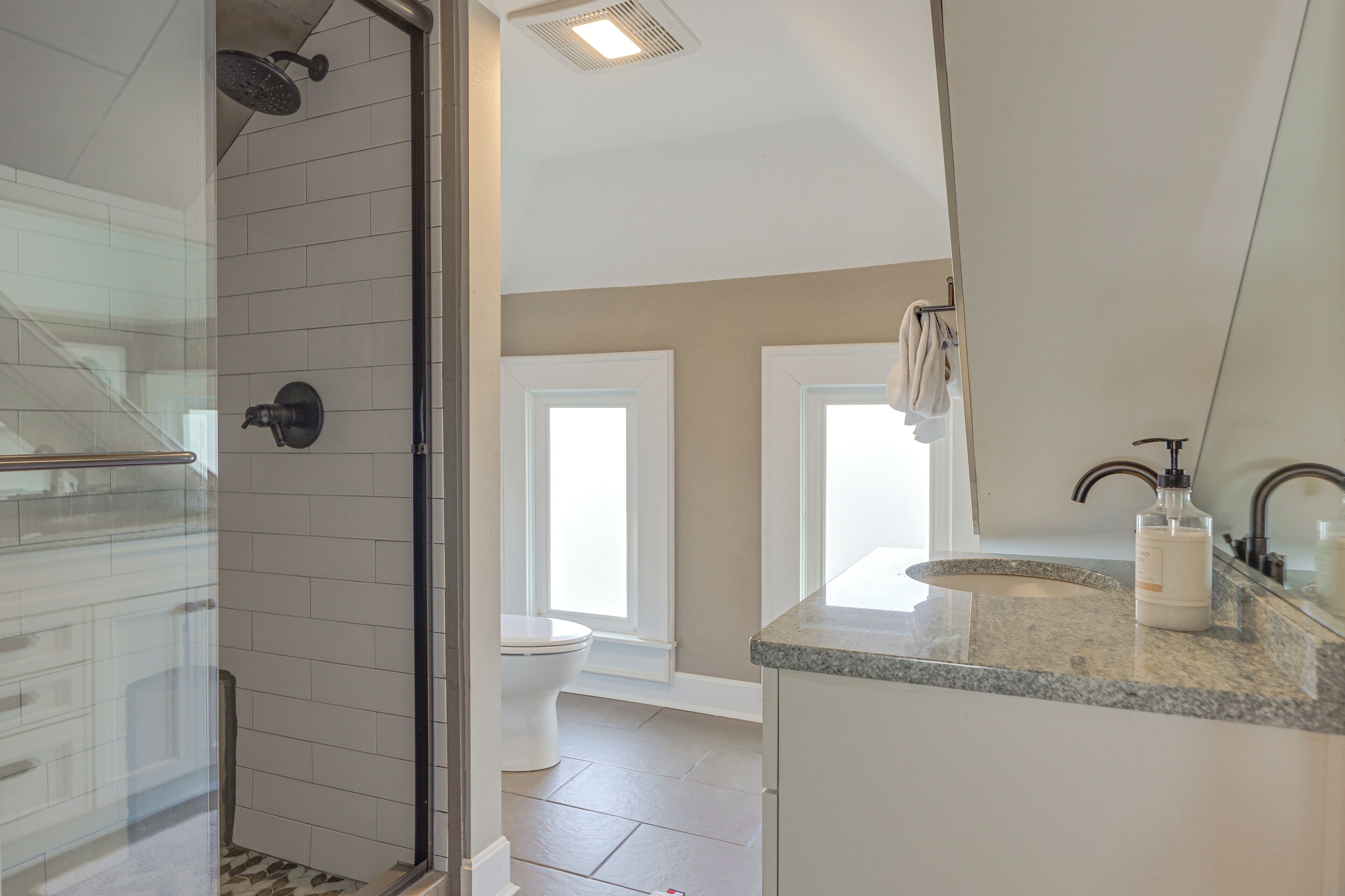 A modern bathroom with a glass shower enclosure, a toilet, and a sink with a mirror.