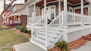 A two-story house with a covered porch, white railings, and a front staircase. - Charming Cincinnati Home w/ Spacious Deck! (Cincinnati)
