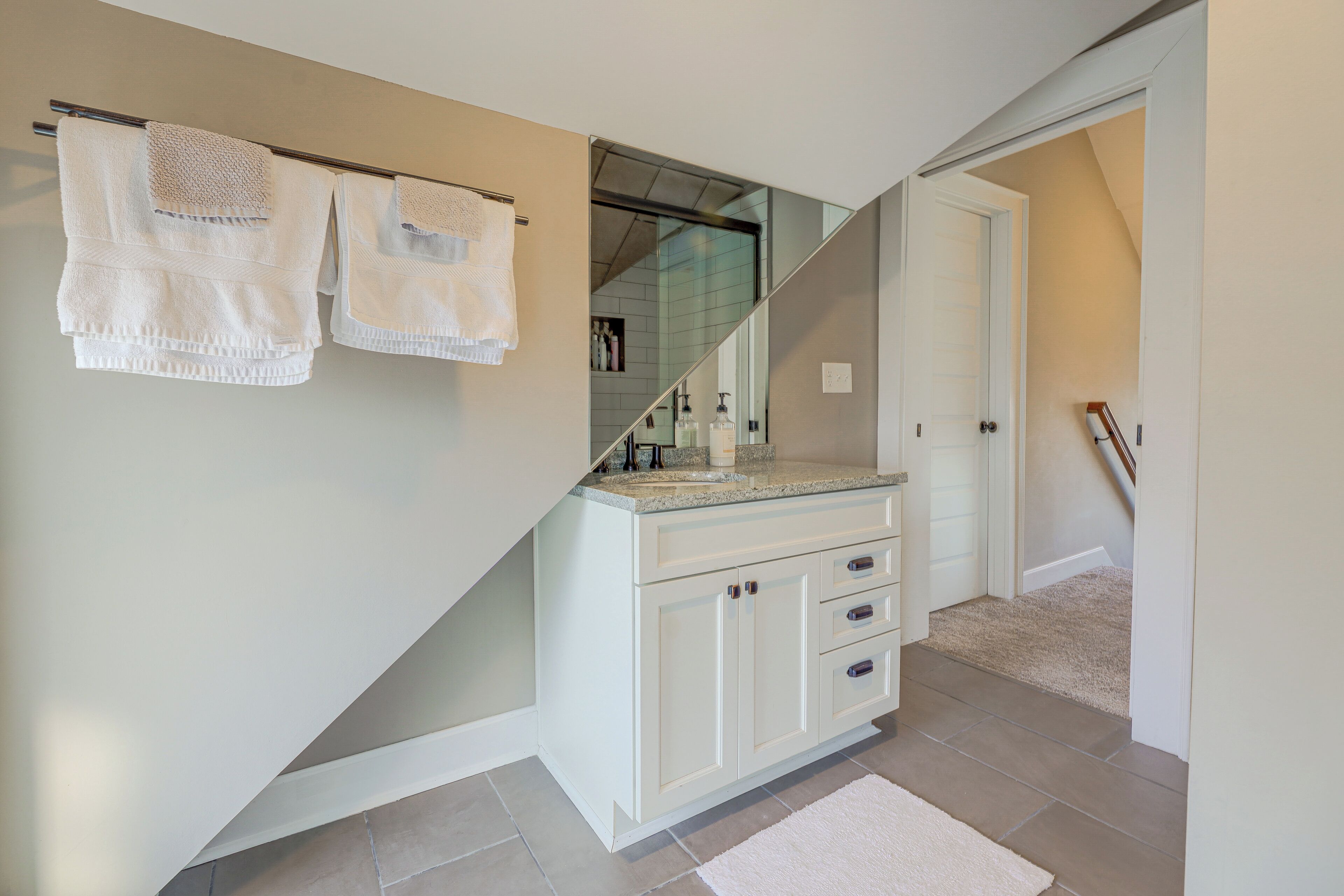 A bathroom with a glass shower enclosure, white cabinetry, and a white towel rack.