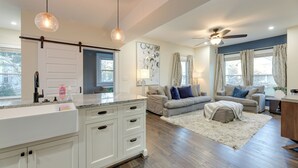 A spacious living area with a kitchen, a ceiling fan, and a large window with curtains. - Charming Cincinnati Home w/ Spacious Deck! (Cincinnati)