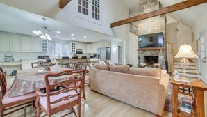 A spacious kitchen with white cabinets, a dining area with a table and chairs, a beige sofa, and a fireplace.