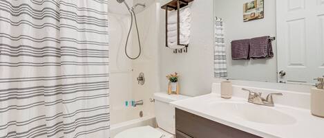 A bathroom with a shower curtain, a toilet, a sink, and a mirror.