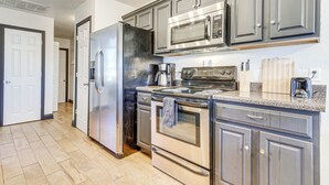 Une cuisine moderne dotée d’appareils électroménagers en acier inoxydable, de meubles de rangement gris et d’un plancher en bois.