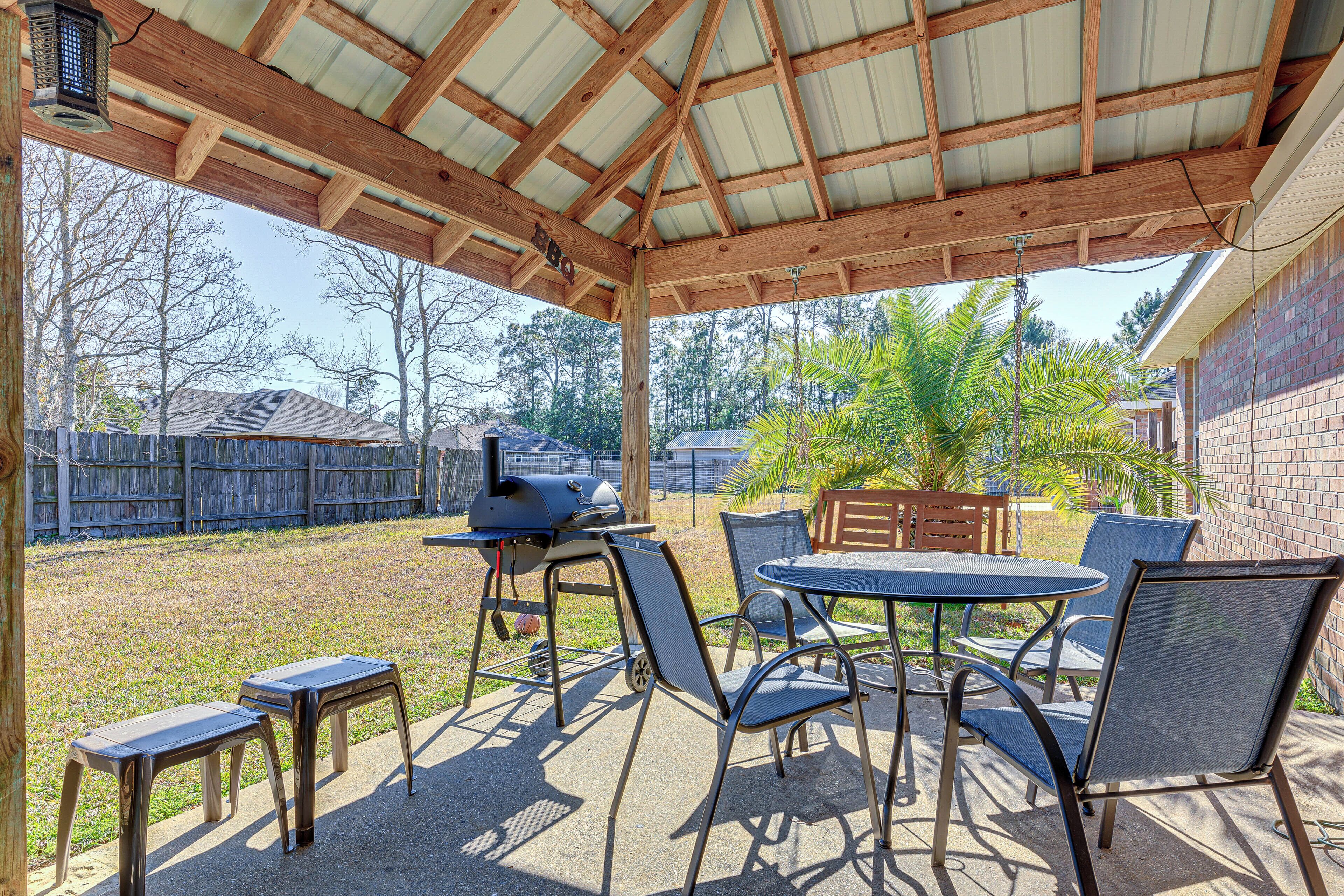 An outdoor patio with a covered area, a grill, and seating.