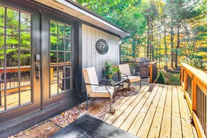 A wooden deck with two chairs and a table, a door with glass panels, and a sign on the wall. - Peaceful Pocono Gem! Cabin 6 Mi to Dtwn Jim Thorpe (Jim Thorpe)