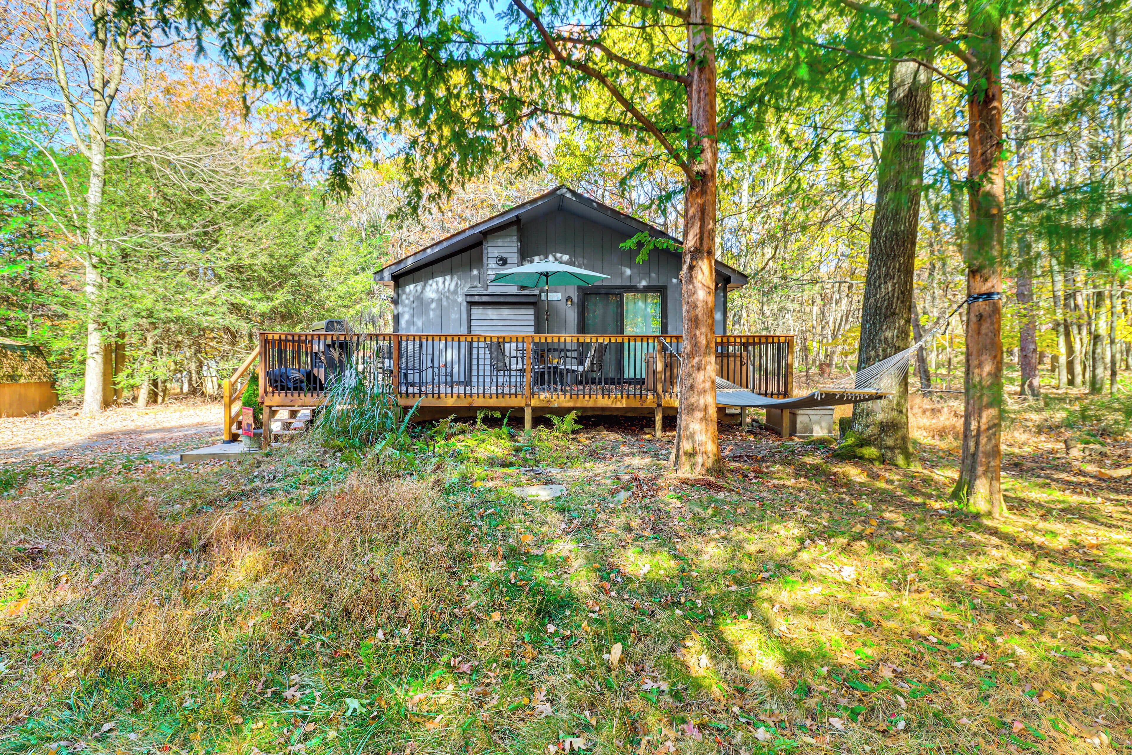 A cabin with a deck, surrounded by trees and a natural setting.