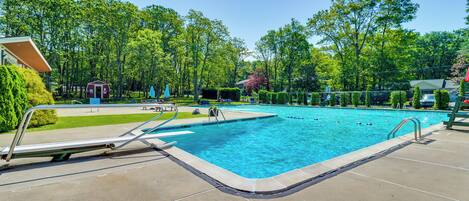 A rectangular swimming pool with a metal ladder on one side, surrounded by a concrete deck.
