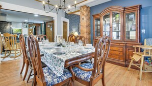 Une salle à manger avec une table en bois dressée pour six personnes, entourée de chaises rembourrées.
