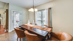 Een eethoek met een houten tafel, lederen stoelen en een kroonluchter.