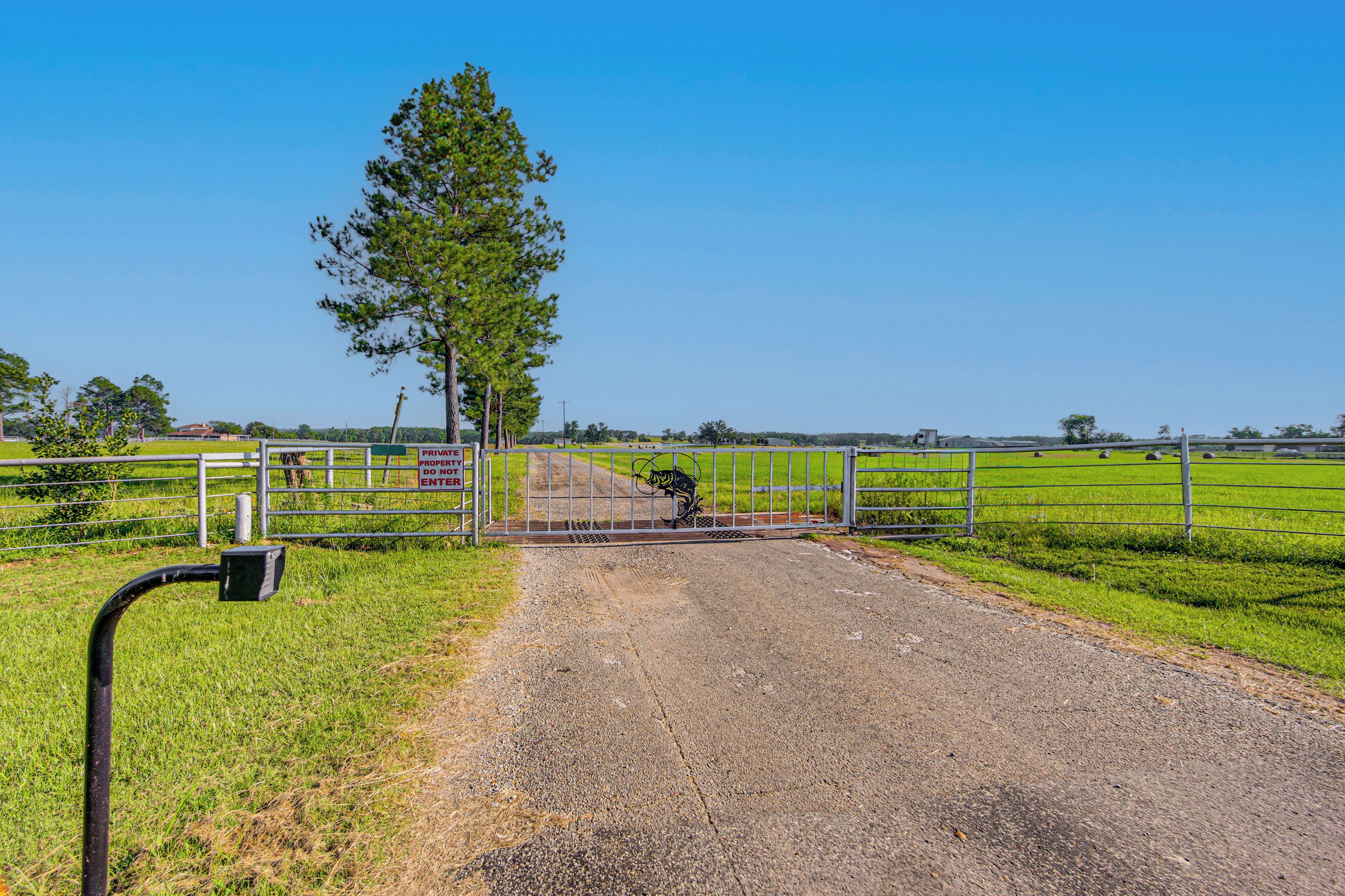 A rural road leading to a gated property with a metal gate and a sign indicating private property.