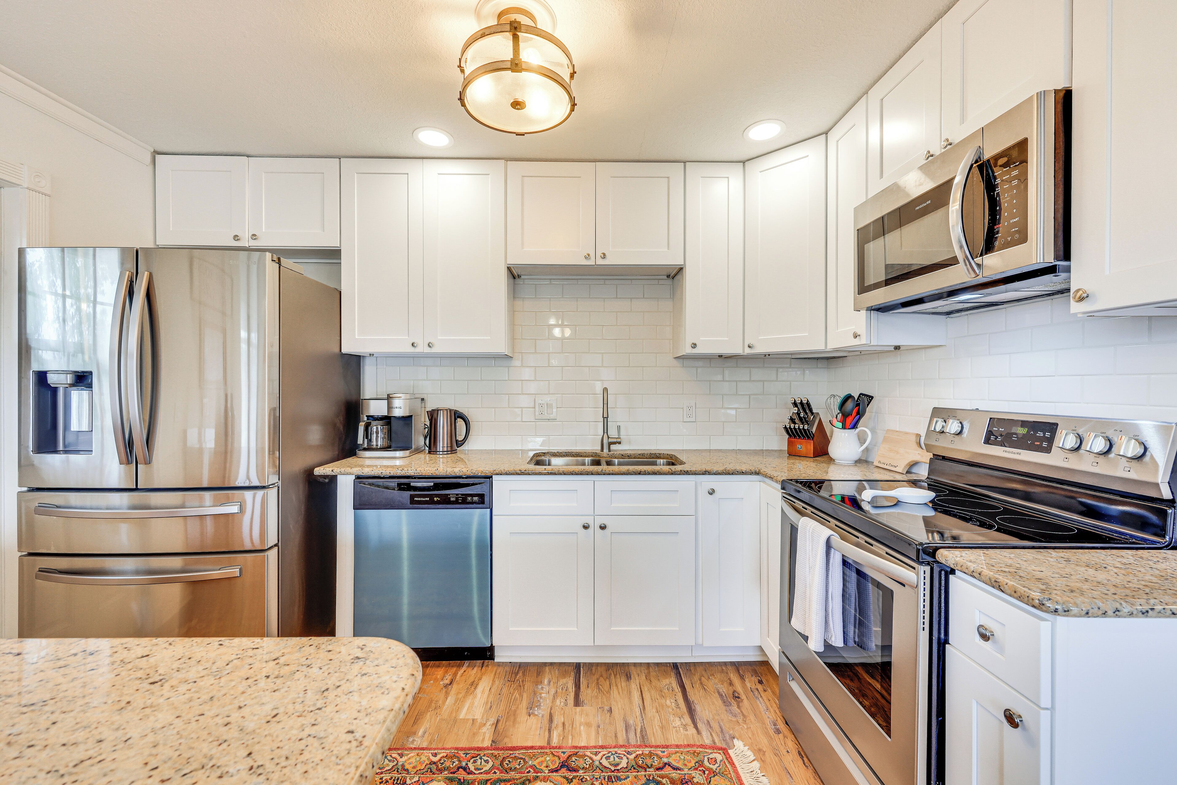 A modern kitchen with white cabinets, stainless steel appliances, and a granite countertop.