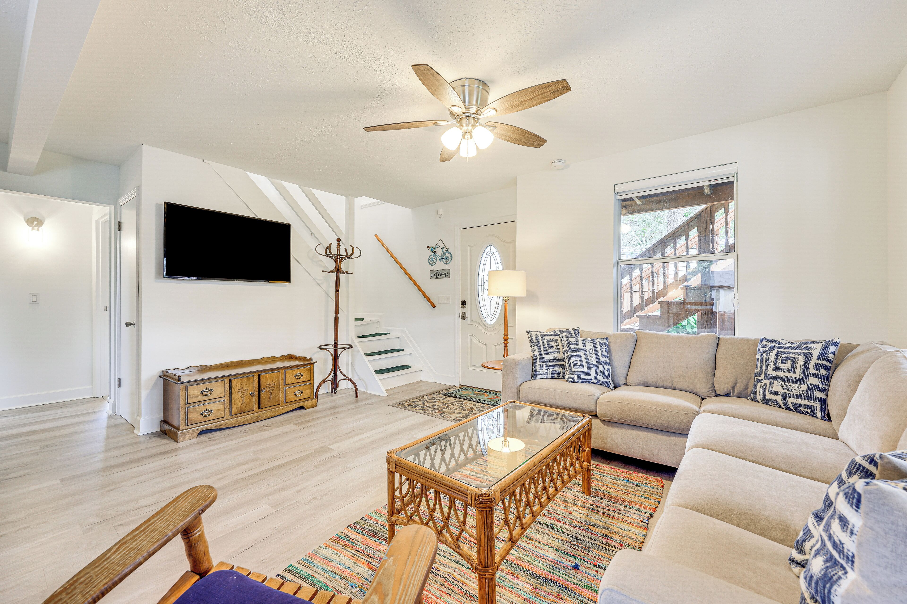 A spacious living room with a ceiling fan, a sofa, a coffee table, and a television on the wall.