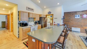 A modern kitchen with wooden cabinets, a granite countertop, and a stainless steel refrigerator. - Charming Duplex w/ Patio: 12 Mi to Grand Targhee! (Driggs)
