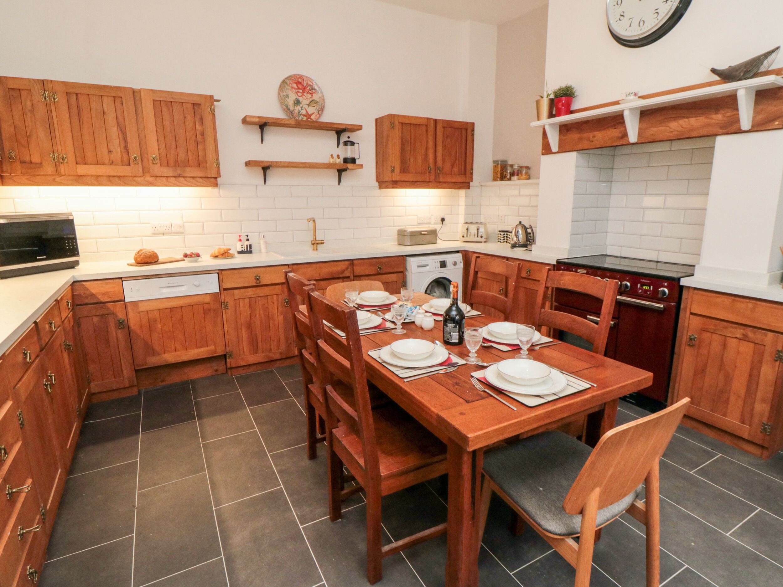 Een kleine keuken met houten kastjes, een eettafel voor vier personen en een inbouwoven.