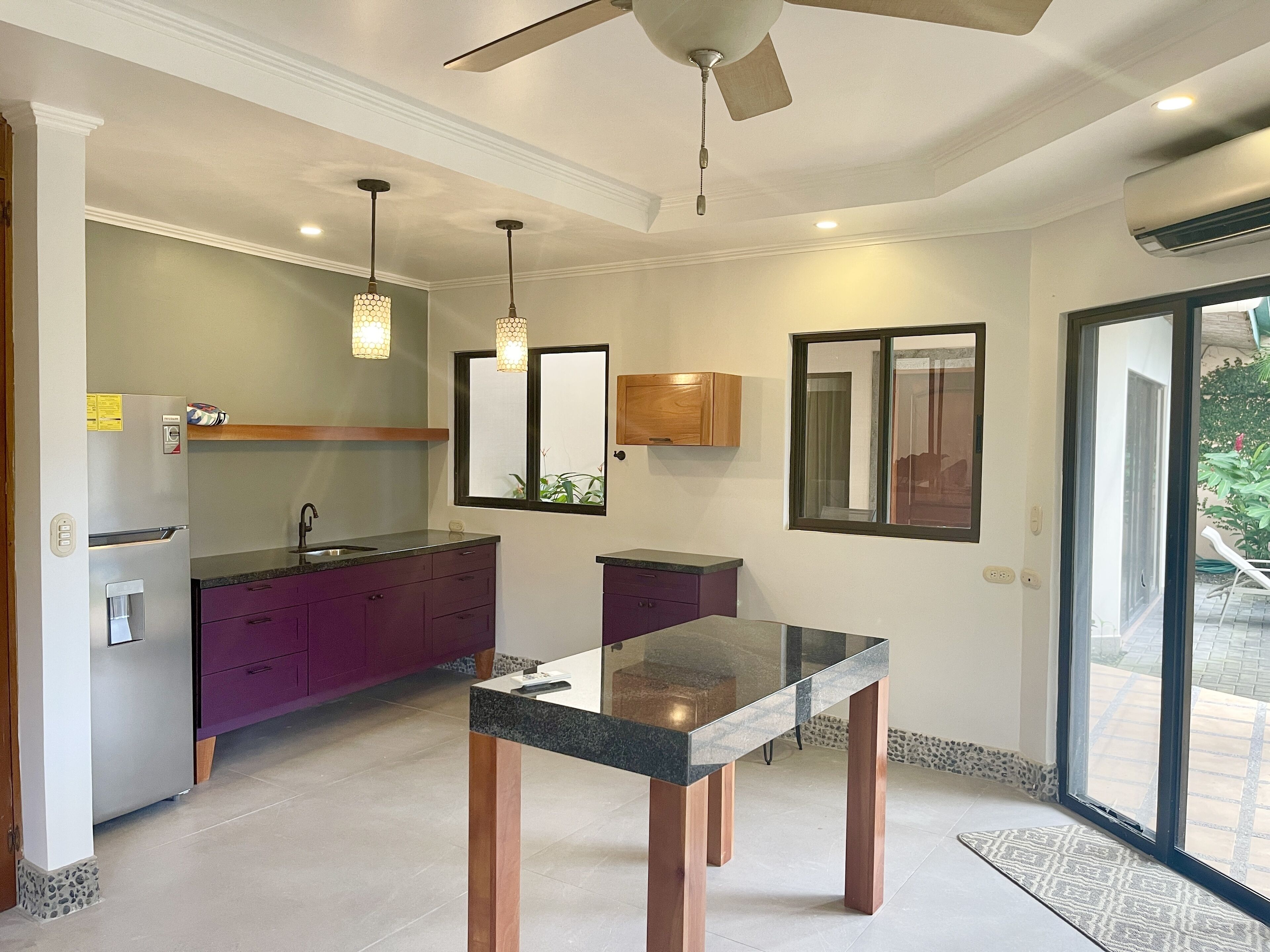 Une cuisine moderne dotée d’un îlot central, de luminaires suspendus et d’un ventilateur de plafond.