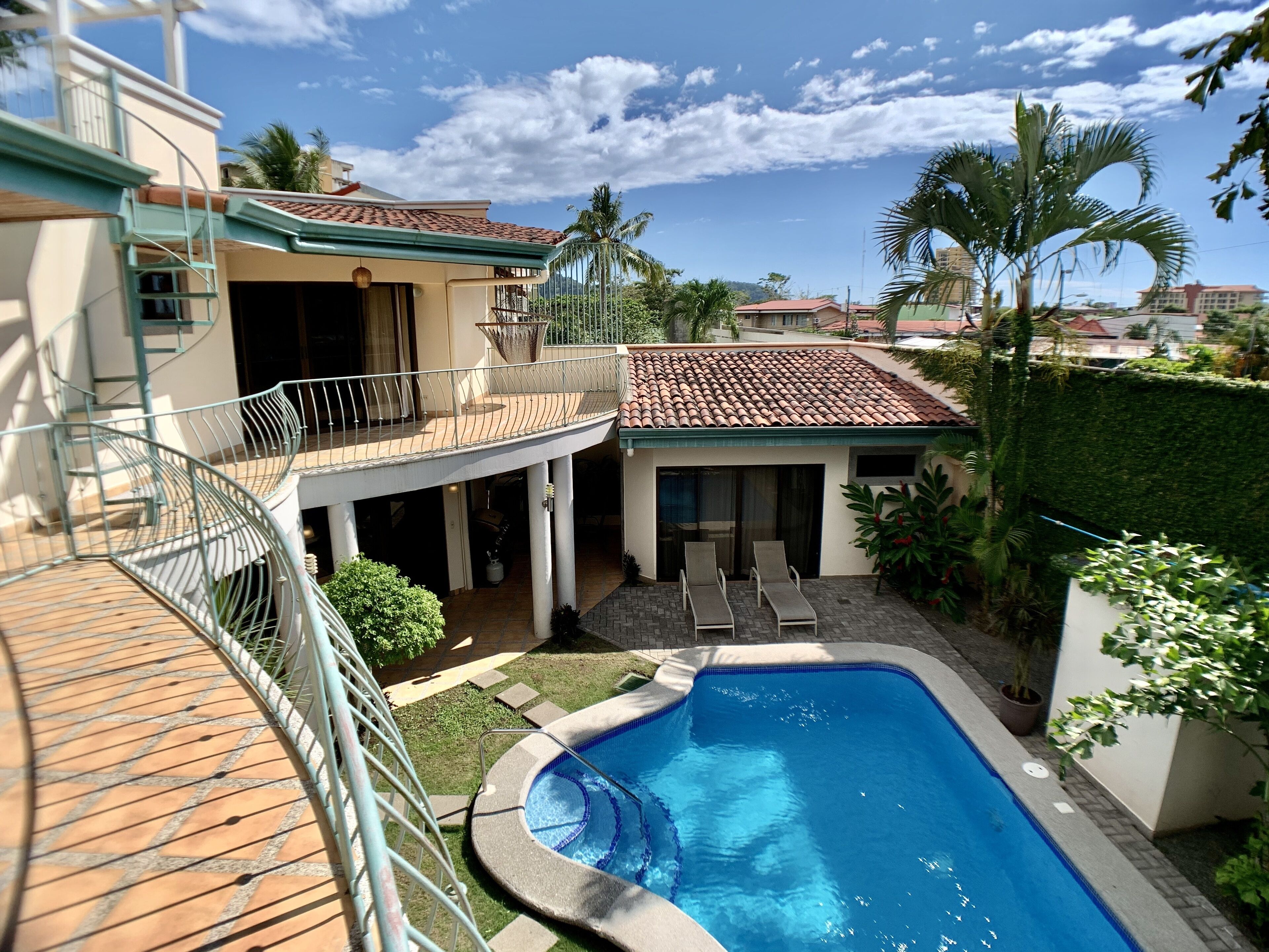 A residential property with a swimming pool, a covered patio, and a balcony.