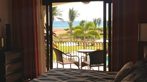 A room with a bed, a view of a pool and beach, and a balcony with chairs and a table. - 3 Bedroom Condo w/ Ocean View - Tres Regalos 201N by RedAwning (Jacó)