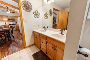 A bathroom with wooden cabinets, a double sink, and a mirror. - Little Little 2 Bedroom Cabin by RedAwning (Sevierville)