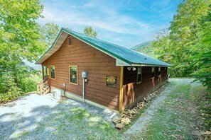 A wooden cabin with a metal roof, surrounded by trees and a gravel path. - Little Little 2 Bedroom Cabin by RedAwning (Sevierville)