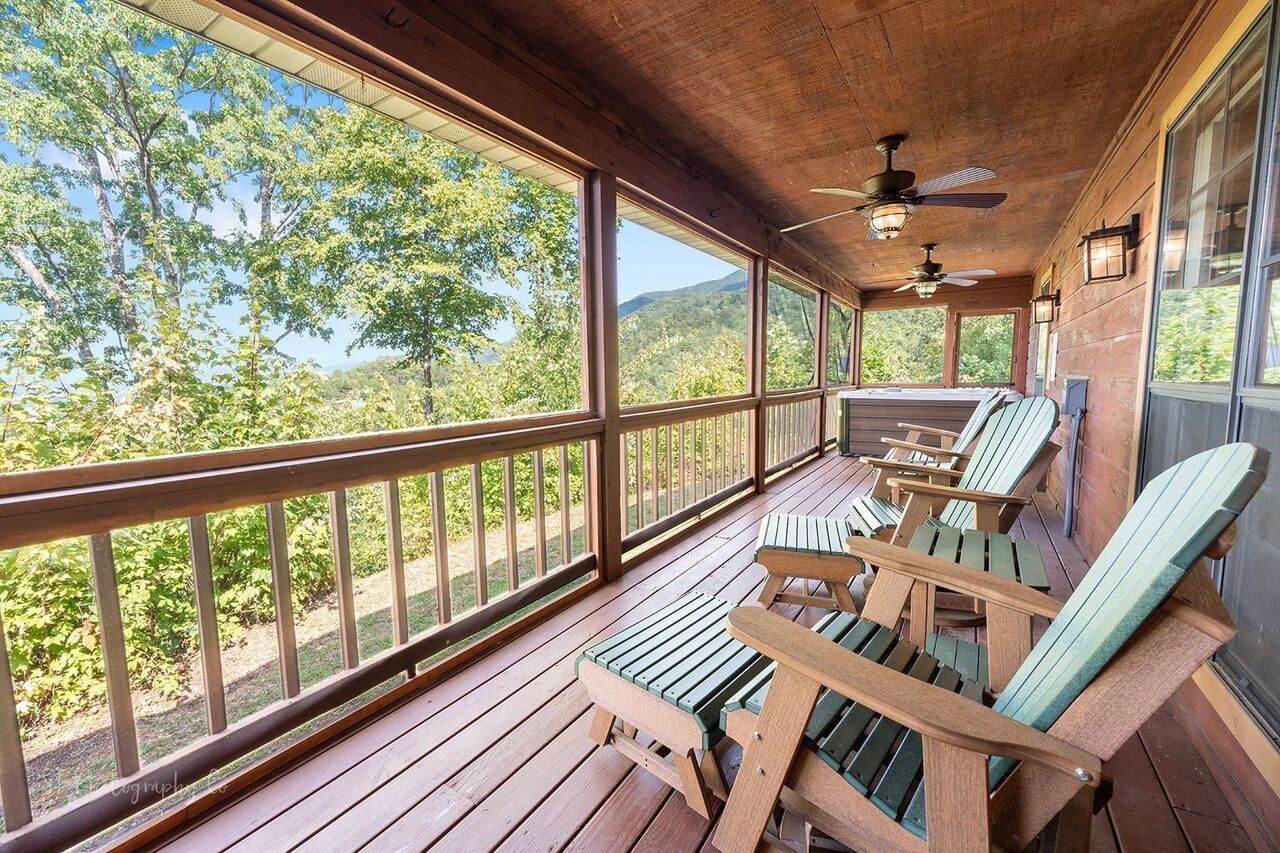 A covered porch with wooden railings, ceiling fans, and outdoor seating.