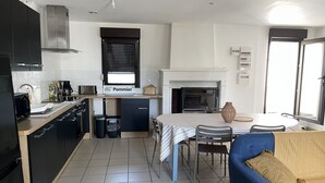 Cocina compacta con comedor, chimenea y sofá.