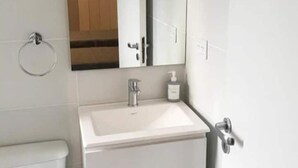 A bathroom with a white sink, a mirror, a toilet, and a towel rack. - Apartamento Céntrico y Luminoso (San Nicolas)