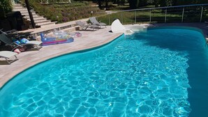A clear swimming pool with a curved edge, surrounded by lounge chairs and a small deck area. - LES FEUILLANTINES (Saint-Cyprien)