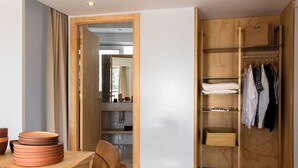 A wooden wardrobe with hanging space and shelves, a wooden table with plates, and a chair. - MOB Hotel Cannes (Cannes)