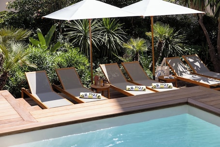 Una piscina al aire libre, sombrillas, sillones reclinables de piscina