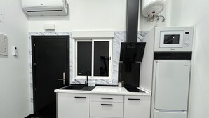 Una cucina compatta con forno a microonde integrato, lavello e frigorifero.