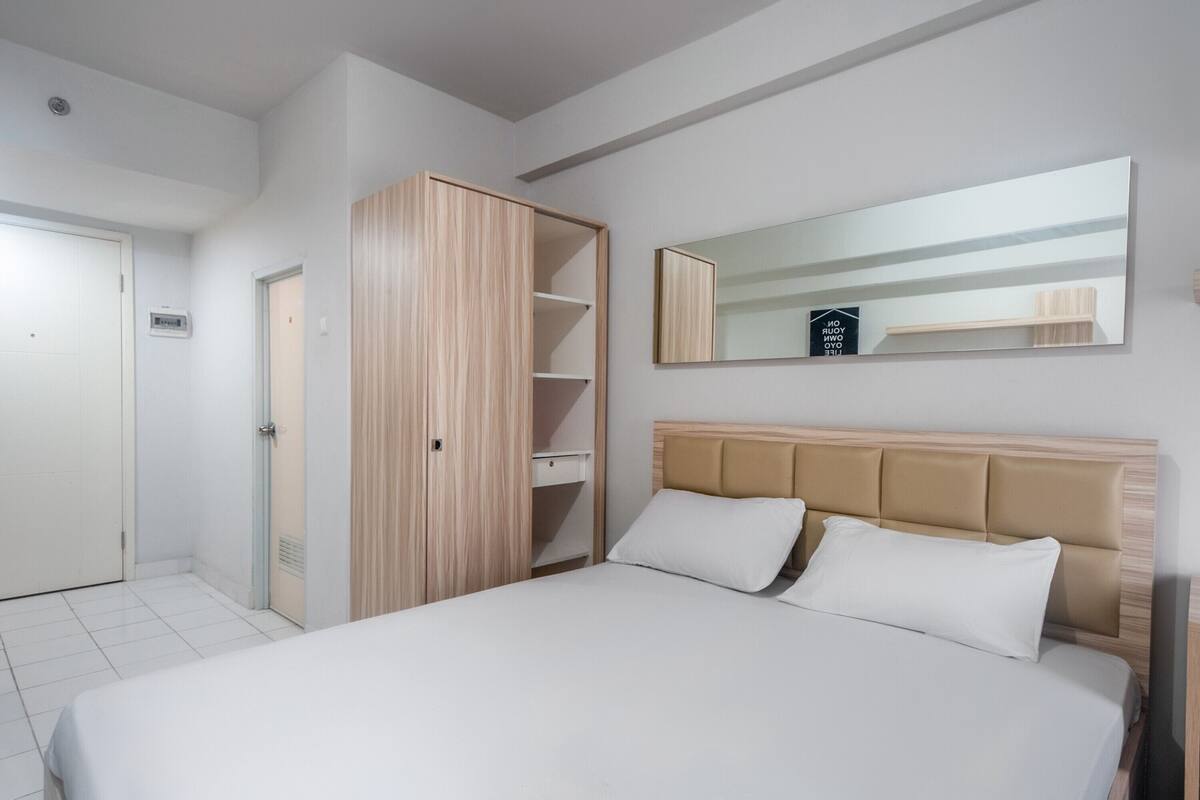 A bedroom with a bed, a wardrobe, and a mirror on the wall.